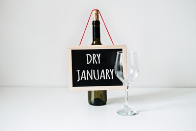 Schild mit Aufschrift "Dry January" neben einer Weinflasche und einem leeren Weinglas