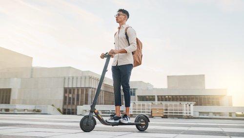 Junger Mann fährt auf einem E-Scooter durch die Stadt