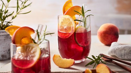 Ein Glas voller Sangria ohne Alkohol, garniert mit Zitrusfrüchten und Rosmarin, ein erfrischendes Getränk für gesellige Anlässe