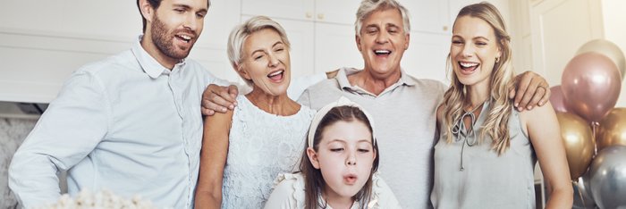 Fröhliche Familie feiert zusammen einen Kindergeburtstag mit einem Kuchen und alkoholfreien Getränken, betont den Wert gemeinsamer alkoholfreier Momente.