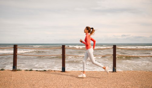 Frau joggt entlang der Küste mit Meerblick