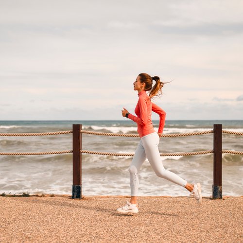 Frau joggt entlang der Küste mit Meerblick