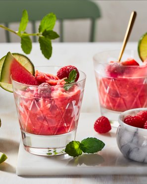 Zwei Gläser mit Wassermelonenslush, dekoriert mit Limitten und Himbeeren