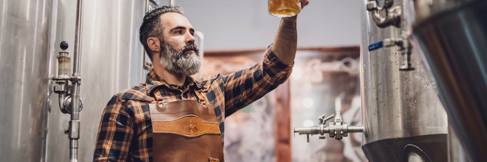 Braumeister prüft die Qualität von alkoholfreiem Bier im Brauereitank, veranschaulicht den Prozess der Herstellung alkoholfreier Getränke auf einer Informationsseite.