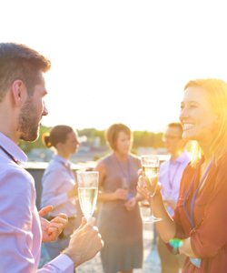 Personen stoßen bei einer Feier im Sonnenuntergang mit Sekt an