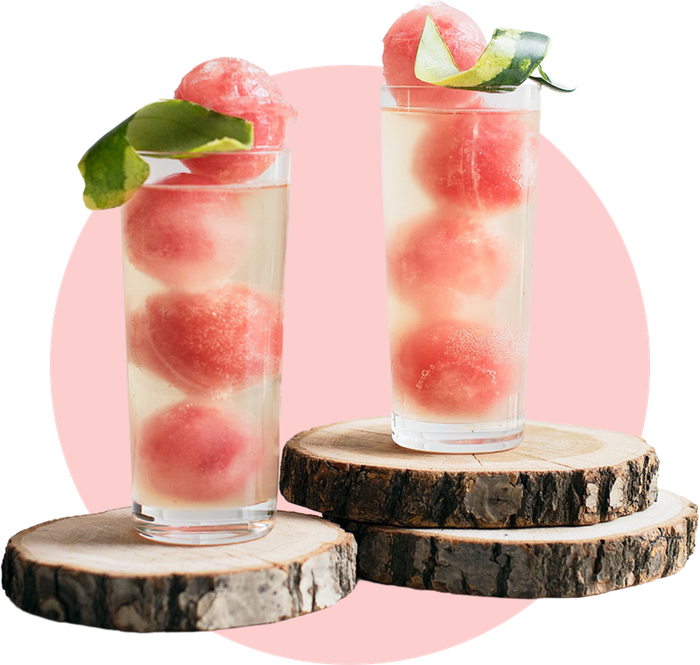 Erfrischende Wassermelonen-Ingwer-Mocktails mit gefrorenen Wassermelonenkugeln und einem Hauch von Ingwer, dekoriert mit Limettenschalen auf rustikalen Holzscheiben