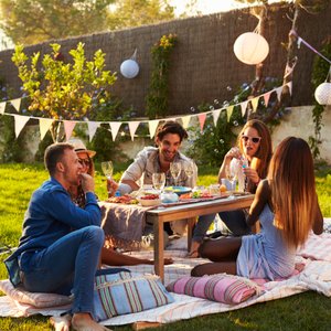 Personen genießen im Freien ein Picknick mit Wein und gesunden Snacks