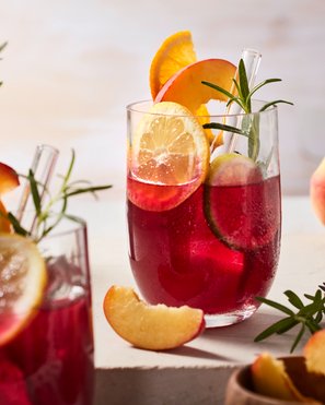 Ein Glas voller Sangria ohne Alkohol, garniert mit Zitrusfrüchten und Rosmarin, ein erfrischendes Getränk für gesellige Anlässe