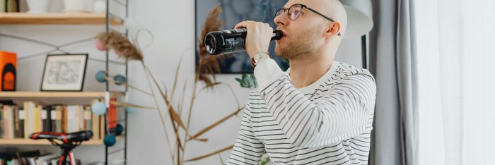 Mann trinkt zu Hause eine Flasche Bier, eine alltägliche Szene mit potentiell hohem Kaloriengehalt